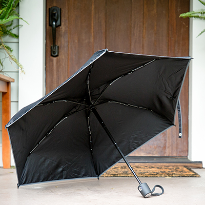 TUMI<sup>&reg;</sup> Small Umbrella - With the push of a button you can open and close this small, portable umbrella. 35" canopy with reflective edging and sure-grip carry handle, rubber wrist strap and storage sleeve make this comfortable to use and easy to stow.  